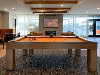 a pool table in a clubroom with a fireplace and a tv on the wall